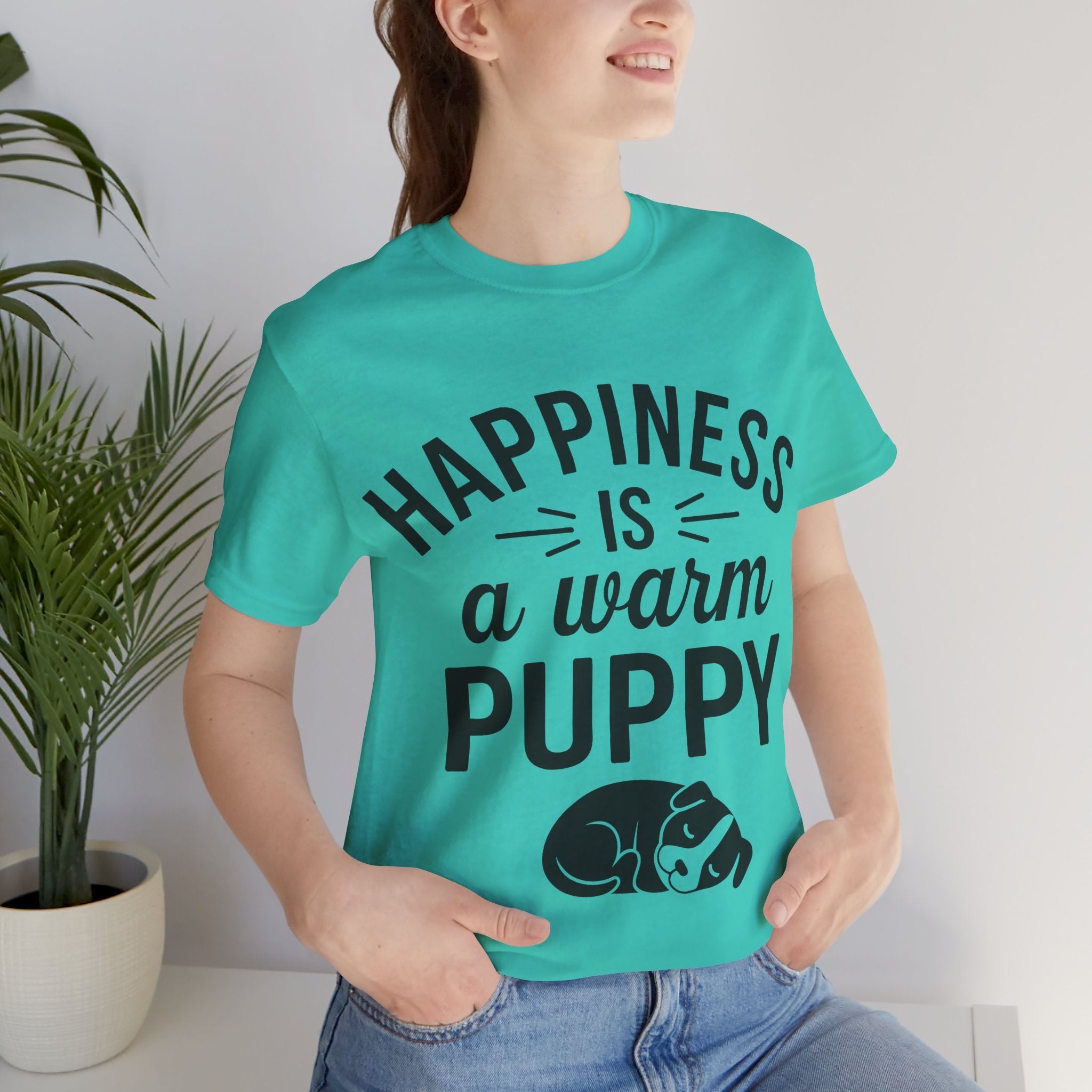 Person wearing a turquoise t-shirt with 'Happiness is a warm puppy' text and graphic.
