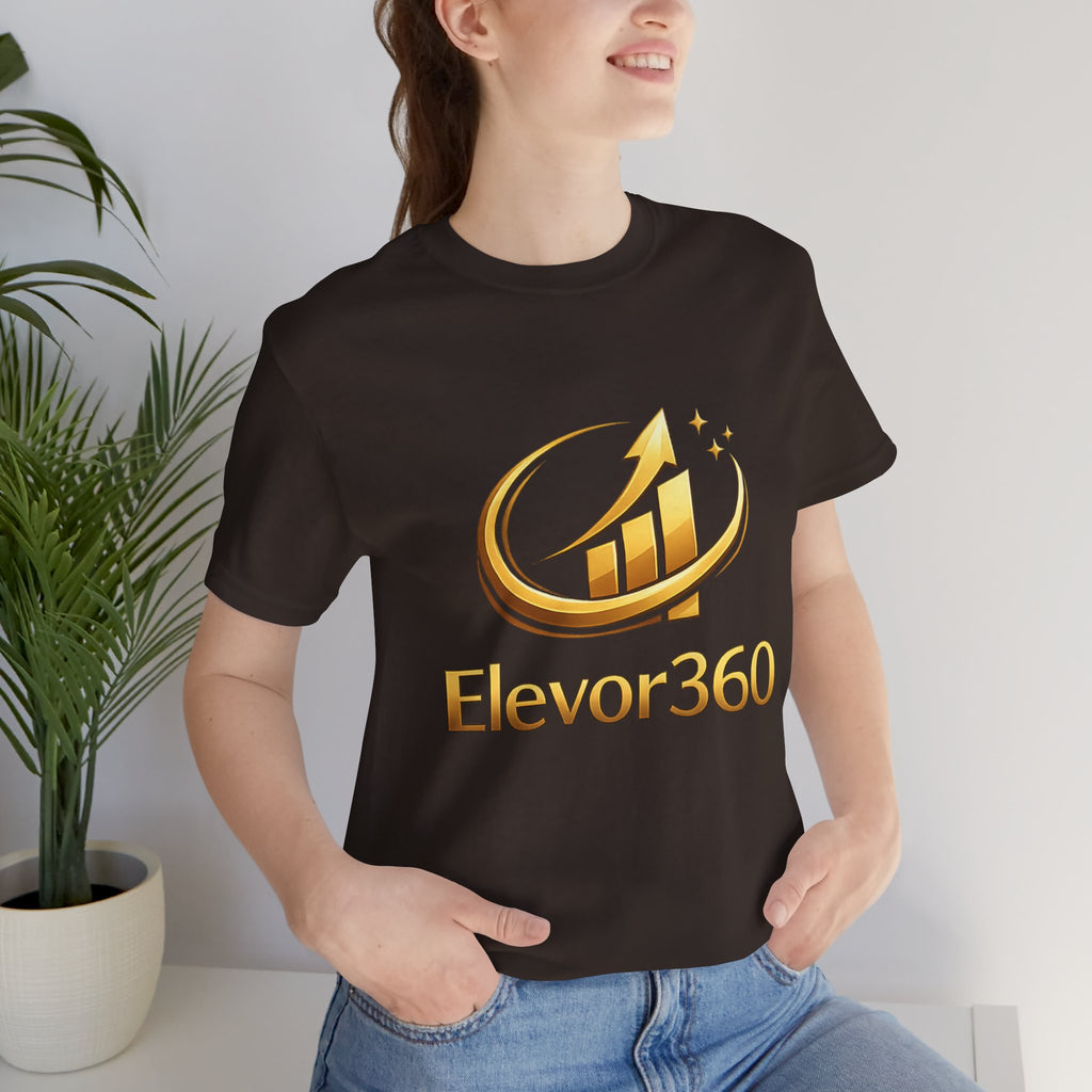 Person wearing a black t-shirt with 'Elevor360' logo in gold, standing indoors next to a plant.