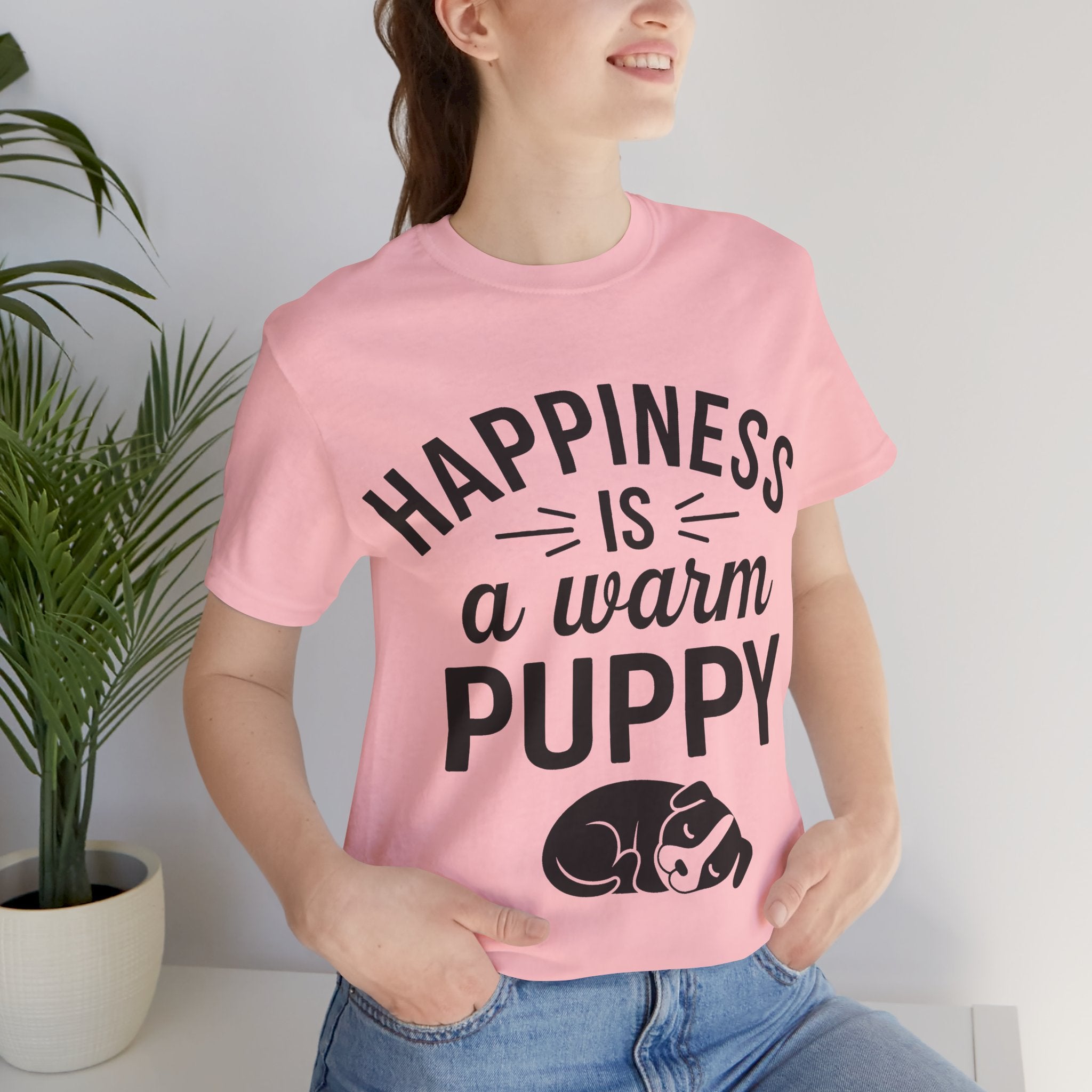 Person wearing a pink t-shirt with 'Happiness is a warm puppy' text and graphic.
