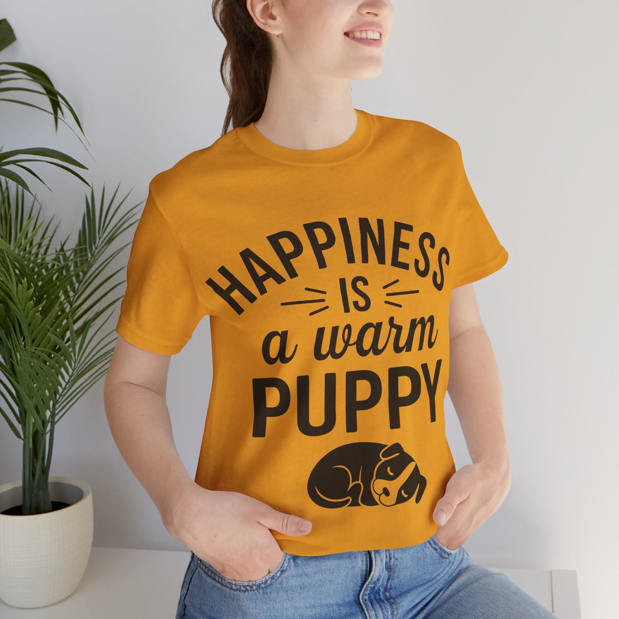 Person wearing a yellow t-shirt with 'Happiness is a warm puppy' text and graphic.