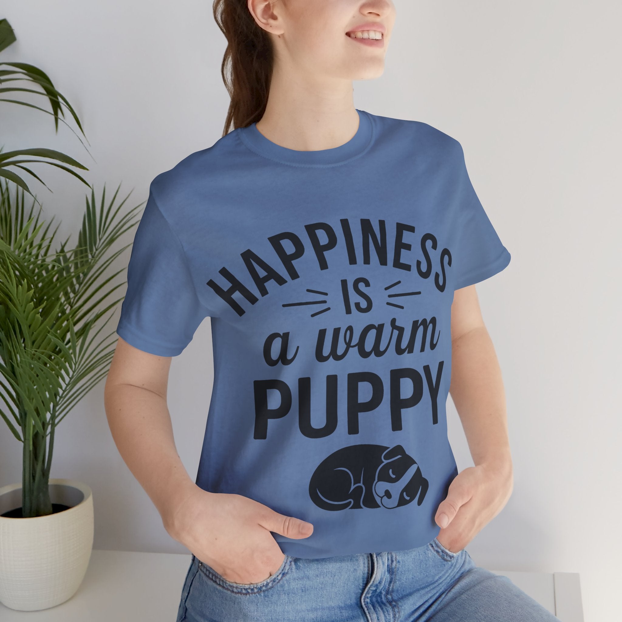 Person wearing a blue t-shirt with 'Happiness is a warm puppy' text and graphic.