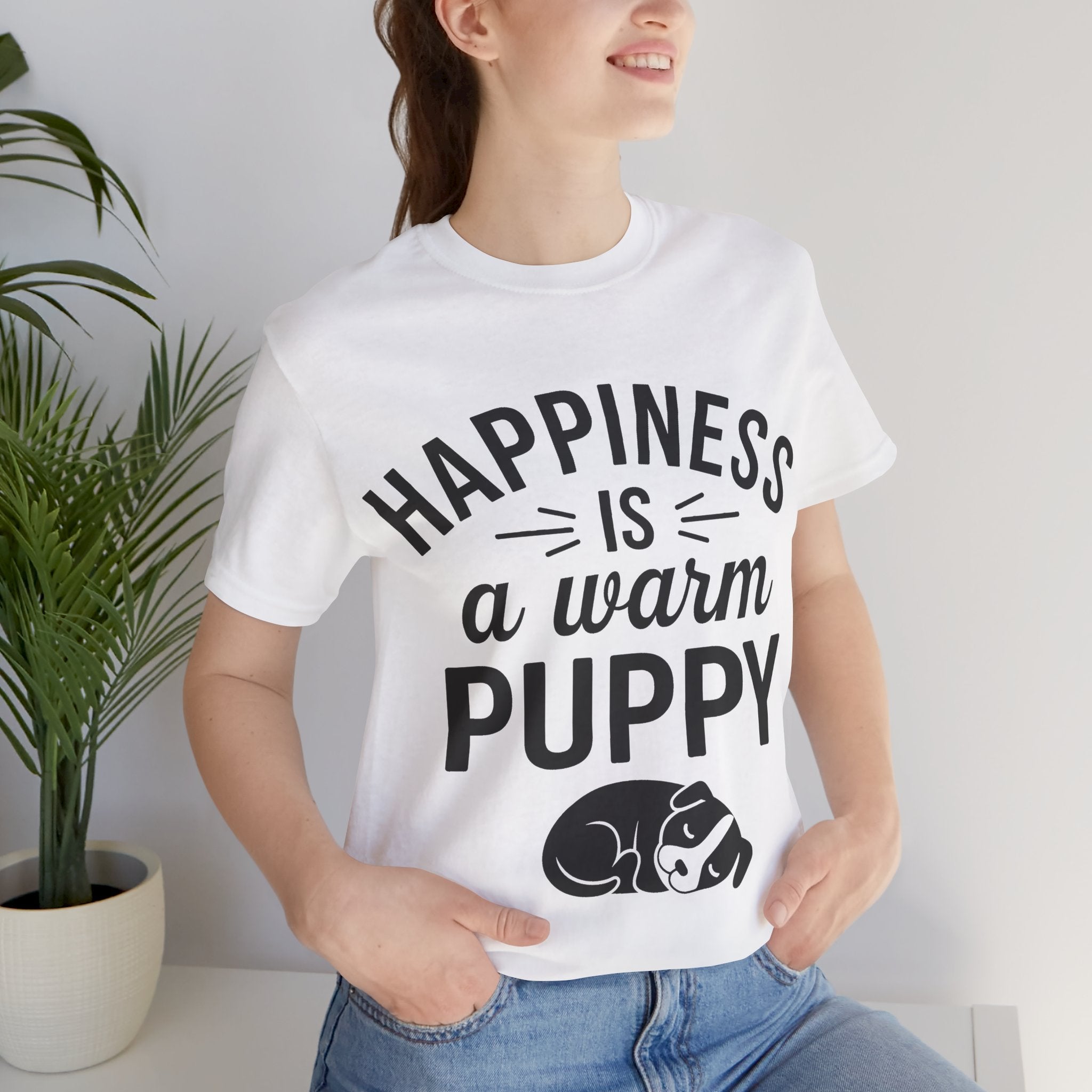 Person wearing a white t-shirt with 'Happiness is a warm puppy' text and graphic.