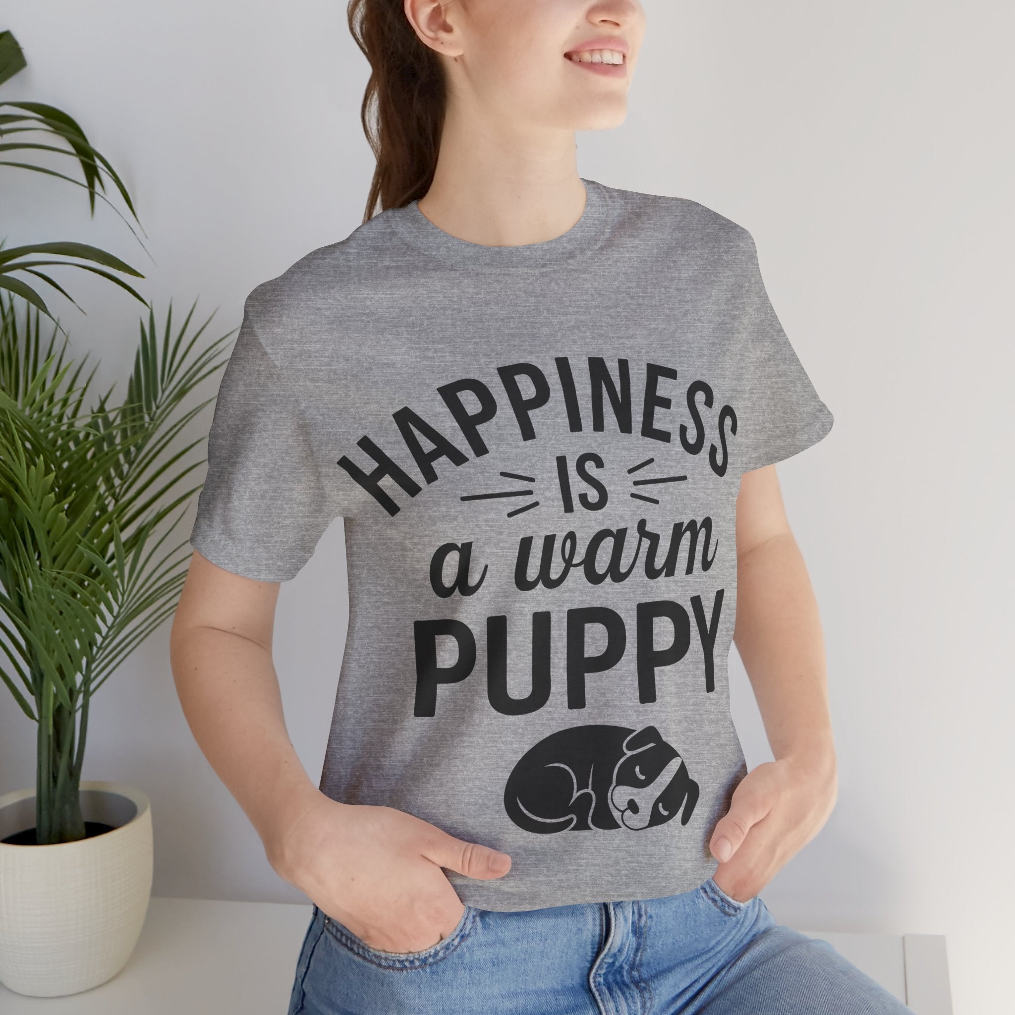 Person wearing a gray t-shirt with 'Happiness is a warm puppy' text and graphic.